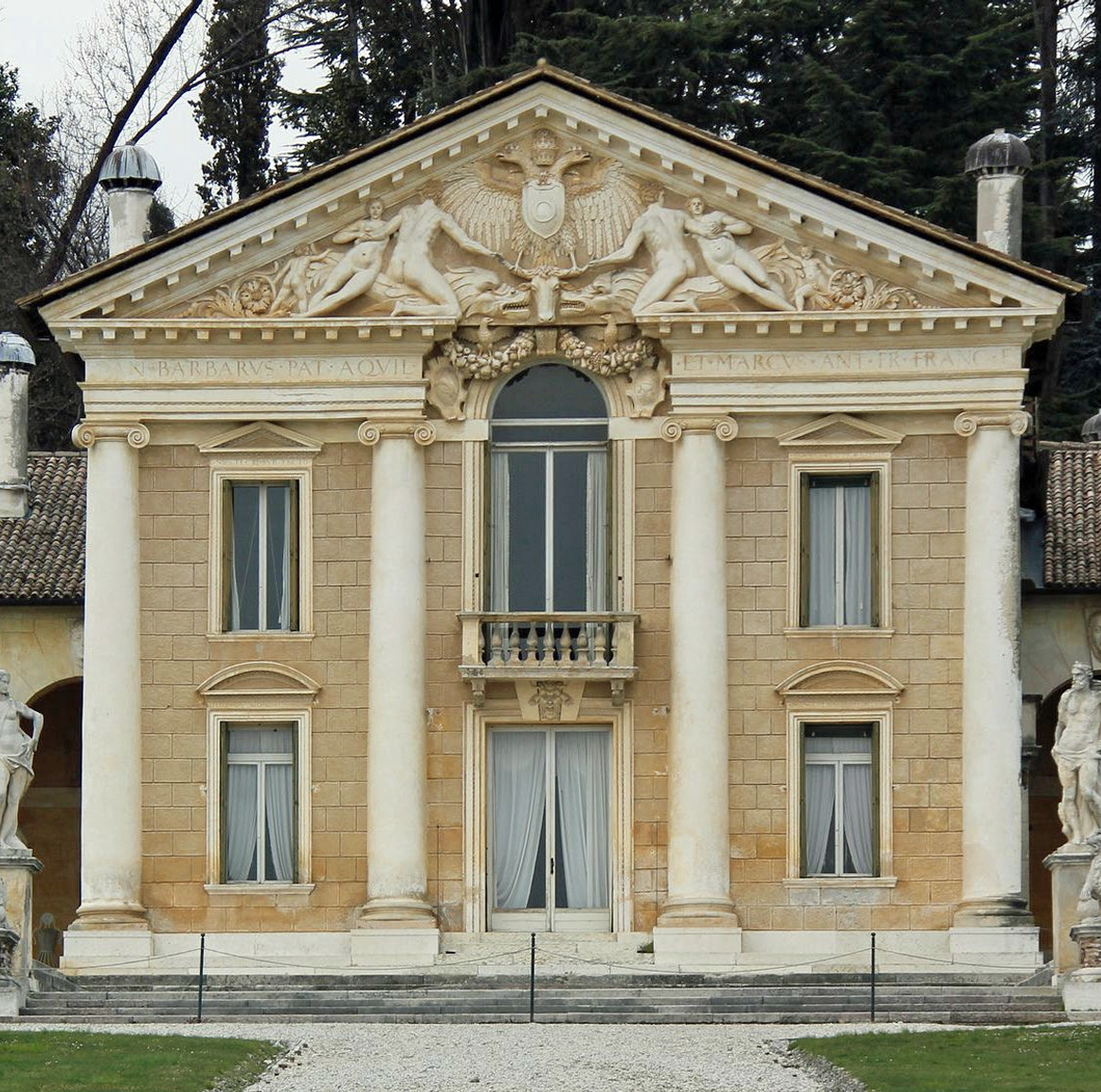 Fassade eines historischen Gebäudes mit Säulen, verziertem Giebel, Balkon und Statuen